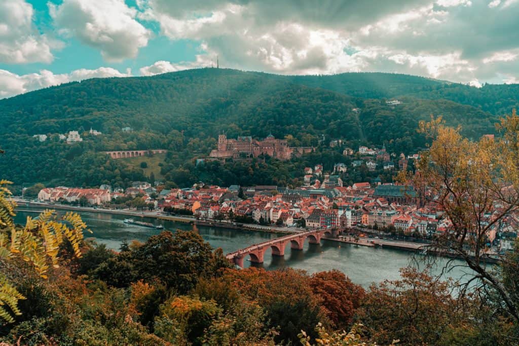 eine Ansicht von Heidelberg mit einer Brücke und Bergen im Hintergrund